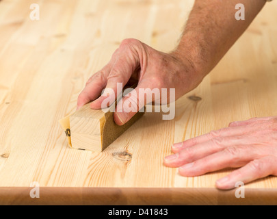 Man using a sanding block on pine floor or table sanding surface Stock Photo