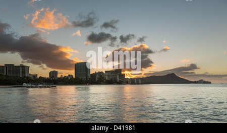 Early morning sunrise at dawn illuminates clouds over Diamond Head and Waikiki Beach area of Oahu in Hawaii Stock Photo