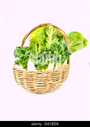 Fresh baby bok choy and cos salad in rattan basket isolated on white background Stock Photo