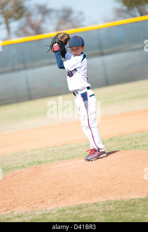 Little league pitcher starting his wind up to pitch to the ball. Stock Photo