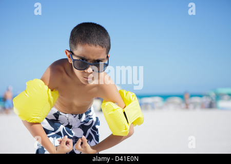 a young latino boy assuming a body builder's pose, flexing his strap-on ...