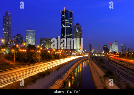 Evening view on illuminated modern office buildings, Azrieli towers and light traces on Ayalon highway in downtown of Tel Aviv. Stock Photo