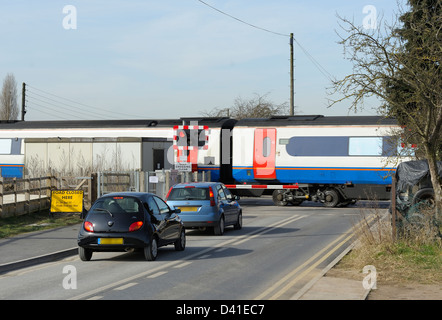 2 cars waiting for a train to pass a barrier level crossing Nottingham england uk number plates blurred. Stock Photo