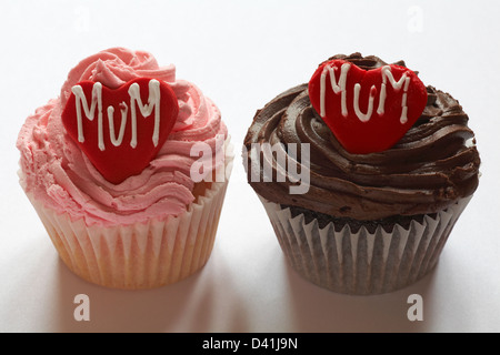 strawberry cupcake and chocolate cupcake with the word mum iced on red heart for Mothering Sunday, Mothers Day isolated on white background Stock Photo