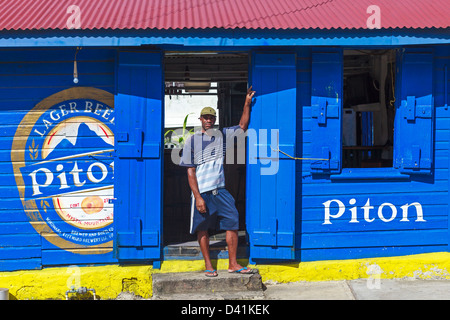 Man standing outside a pub selling the local beer 'Piton' in Vieux Fort, St Lucia Stock Photo