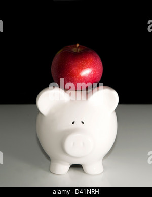 Piggy bank with apple on top of its head Stock Photo