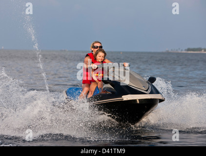 Woman and child on jet ski with water spray, Kuda Hura, Maldives Stock Photo