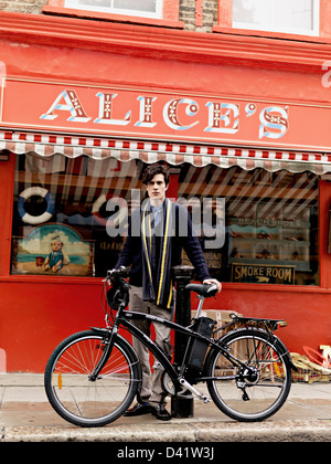 Man standing with  electric bike, in front of shop window, London, UK Stock Photo