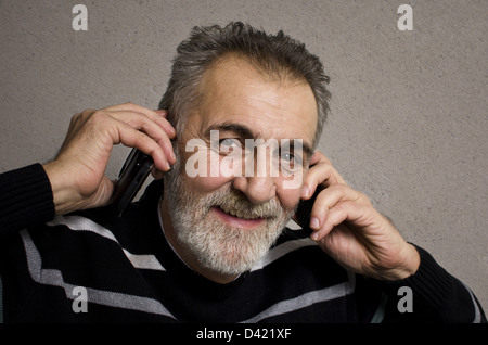 Portrait of a smiling mature man with two mobile phones Stock Photo