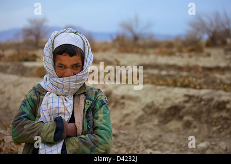 Kandahar, Afghanistan - January 10, 2011: An Afghan boy escapes the cold January weather in an old lined field jacket. Stock Photo