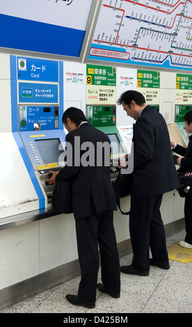 Businessmen purchasing train tickets from vending machines inside Ueno Station, Tokyo. Stock Photo