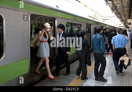 Commuters getting on and off the green Yamanote Loop Line train at the Ueno Station platform in Tokyo. Stock Photo