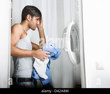 Man Having Problems Operating the Washing Machine on Laundry Day Stock Photo