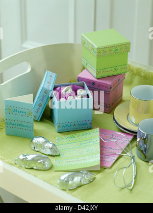 Close-up of pastel colored decorated gift boxes with sugar mice in silver foil on cream tray table Stock Photo