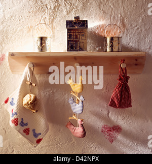Close-up of punched tin candle holders on wooden shelf with Shaker-style gingham bag and cloth ducks on peg rail Stock Photo
