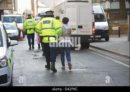 Woman under arrest is led away from the EDL holding pen in Albert Square. Demonstration passes off relatively peacefully - with a massive police operation keeping far right English Defence League (EDL) supporters and  opponents, led by Unite Against Fascism (UAF), apart as they converged on Albert Square. Manchester, England, UK. Saturday 2nd March 2013 Stock Photo