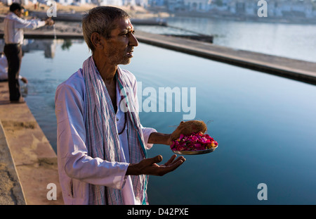 Hindu Brahmin priest offers votive offerings and prayers to the Sun God at the holy lake in Pushkar, Rajasthan, India. Stock Photo