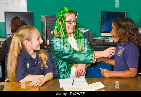 Two 7 year old happy female students receive sticker from teacher in leprechaun costume Stock Photo