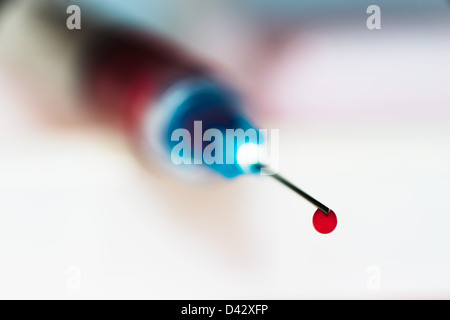 Close up of syringe needle point with drop of blood. Stock Photo