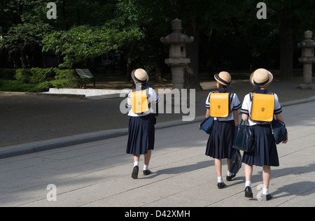 Three Japanese middle school girls wearing sailor uniforms and cute hats walking on their way home from school in Tokyo. Stock Photo