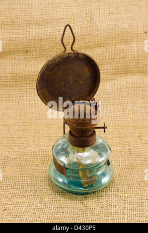 rusty retro kerosene lamp on burlap rural background. Stock Photo