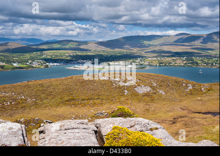 Berehaven Harbour and the fishing port of Castletownbere from Bere Island, with yellow flowering dwarf gorse (Ulex gallii) n the foreground Stock Photo