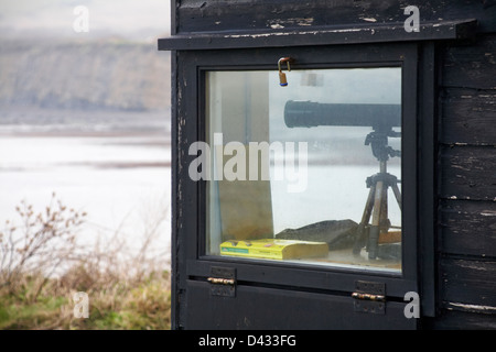 looking out to sea - telescope in range wardens hut at Kimmeridge Bay in February Stock Photo