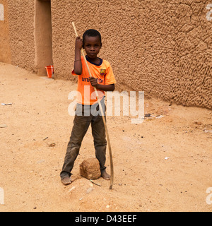 Boy in orange T-shirt holds a stick in Agadez Stock Photo
