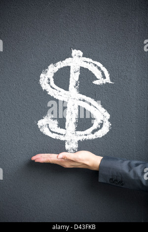 Business man's hand in front of dollar sign written on a blackwall. Concept about money and success. Stock Photo