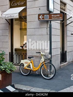 Bike Mi rental bicycle outside Cartier designer luxury watch store Milan Lombardy Italy Europe Stock Photo