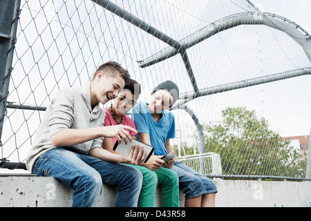 Three Boys Playing Video Games in Playground, Mannheim, Baden-Wurttemberg, Germany Stock Photo