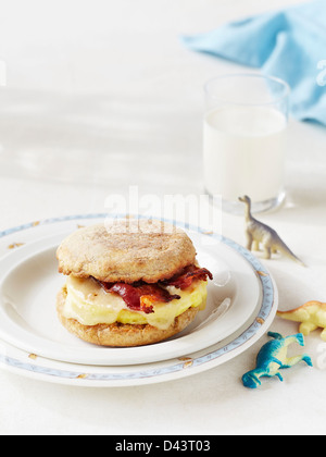 Scrambled Egg and Bacon on English Muffin with Toy Dinosaurs on Table Stock Photo