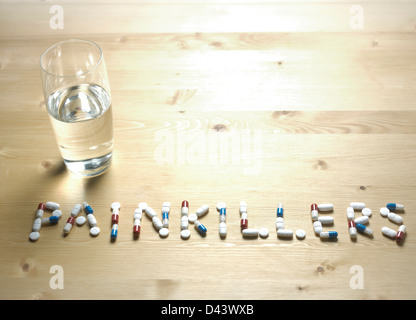 Painkillers slogan written with pills on wooden table Stock Photo