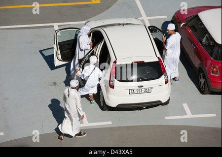 Muslim family in traditional white clothing get into a saloon car Stock Photo