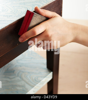 Close-up of Woman's Hand using Sanding Sponge on Table in Studio Stock Photo