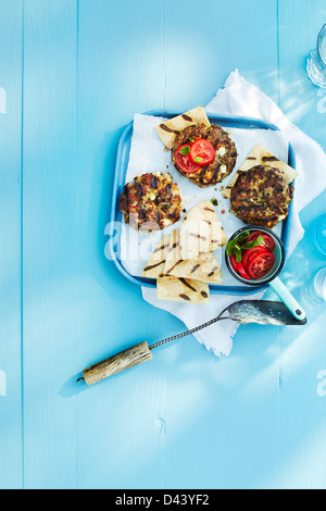 Grilled Burgers and Pita Bread on Tray with Spatula on Blue Wooden Table in Studio Stock Photo