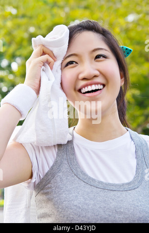 Asian woman wiping sweat with a towel after exercising Stock Photo