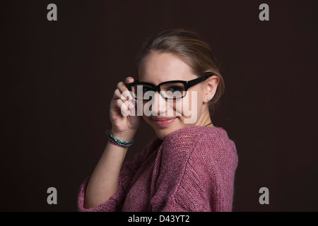 Close-up Portrait of Blond, Teenage Girl wearing Eyeglasses and Looking at Camera, Studio Shot on Black Background Stock Photo
