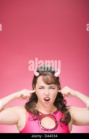 Portrait of Woman Wearing Devil Horns and Plugging Ears Stock Photo