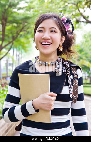 young pretty asian woman walking with laptop in modern park street on ...