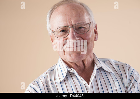 Portrait of Senior Man wearing Aviator Eyeglasses, Looking at Camera Smiling, in Studio on Beige Background Stock Photo