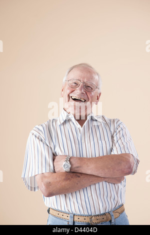 Portrait of Senior Man wearing Aviator Eyeglasses, Looking at Camera Laughing, in Studio on Beige Background Stock Photo