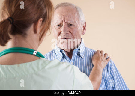 Senior Man being Examined by Medical Health Care Provider in Medical Office, Studio Shot on Beige Background Stock Photo