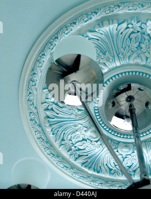 Pastel blue plaster ceiling rose and chrome and glass light fitting Stock Photo