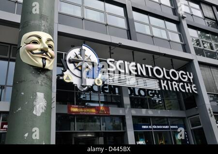 An Anonymous mask (also: Guy Fawkes Mask or Vendetta Mask) is pictured on a light pole in front of the Scientology church at Otto-Suhr-Allee in Berlin, Germany, 24 August 2011. Above the door, the writing 'Scientology Kirche' and the Scientology cross are installed Underneath in the interior of the building the writing 'Find it out for yourself' can be read. Fotoarchiv für ZeitgeschichteS.Steinach Stock Photo
