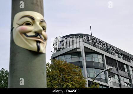 An Anonymous mask (also: Guy Fawkes Mask or Vendetta Mask) is pictured on a light pole in front of the Scientology church at Otto-Suhr-Allee in Berlin, Germany, 24 August 2011. View of the writing 'Scientology Kirche' and the Scientology cross on the top of the building. Fotoarchiv für ZeitgeschichteS.Steinach Stock Photo