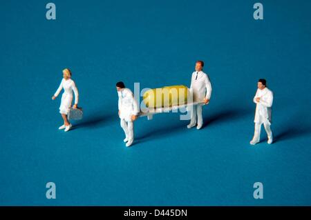 Illustration - Miniature figures in white coats carry a stretcher with a yellow tablet in Berlin, Germany, 25 December 2007. Fotoarchiv für ZeitgeschichteS.Steinach Stock Photo