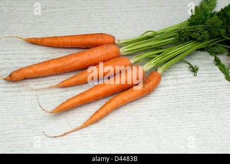 Organic carrots with tops on against a light wooden background Stock Photo