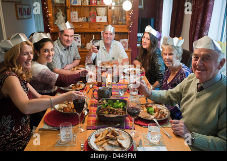 Horizontal portrait of three generations of a family enjoying Christmas lunch together round the table. Stock Photo