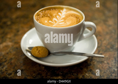 Horizontal close up of a cup of coffee with a decorative pattern made on the top. Stock Photo